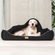 Ein großer weißer Hund liegt bequem in einer schwarzen Haustierliege mit einer teilweise darüber liegenden Decke, vor einem minimalistischen Hintergrund.