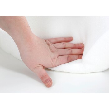 Eine Hand drückt auf eine weiche, weiße Schaumoberfläche und demonstriert deren Polsterung und Komfort.