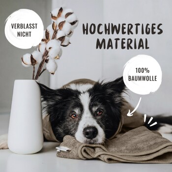 Schwarz-weißer Hund ruht den Kopf auf einem gefalteten braunen Handtuch, Baumwollpflanze in weißer Vase daneben, Text "Hochwertiges Material," "Verblasst nicht," "100% Baumwolle."