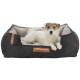 Ein gemütliches dunkelgraues Hundebett mit beigem Innenraum und Ledergriff, mit einem kleinen weißen Hund, der darin entspannt.