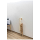 Eine hellorange Katze streckt sich, um einen wandmontierten Kratzbaum in einem modernen Wohnraum mit Holzboden und einem grauen Sofa zu kratzen.