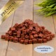 Haufen Lammfleischwürfel auf einem Holzbrett mit Pflanze, goldene ‚PREMIUM‘-Schleife und Etikett ‚Lammfleisch-Würfel‘