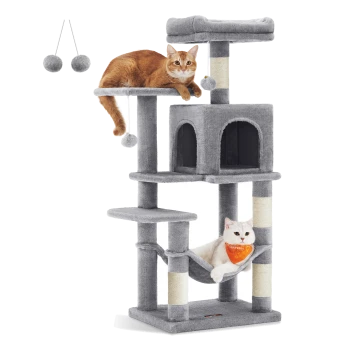 Zwei Katzen, eine orangefarbene Tabby und eine weiße Katze, entspannen sich auf einem mehrstöckigen grauen Katzenbaum mit hängenden Pompons und einer Hängematte.