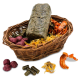 Ein geflochtener Korb voller verschiedener Haustierleckerlis, darunter ein grüner Block, lila Bälle, getrocknete Orangenschnitze und gelbe Blumen.