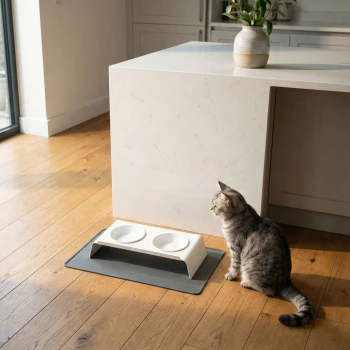 Eine graue Futtermatte für Haustiere wird oben gezeigt, mit einer gerollten beigen Matte links und einer gerollten rosa Matte rechts.