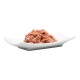 Eine Portion Haustierfutter, die auf einem weißen Teller präsentiert wird, mit einer strukturierten, rosafarbenen Fleischmischung mit kleinen orangefarbenen Flecken.