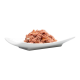 Eine Portion Haustierfutter, die auf einem weißen Teller präsentiert wird, mit einer strukturierten, rosafarbenen Fleischmischung mit kleinen orangefarbenen Flecken.