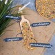 Eine Holzschaufel mit buntem Vogelfutter auf Jute, umgeben von Gras, mit Etiketten: "reich an Protein", "natürlich", "artengerecht", "abwechslungsreich."