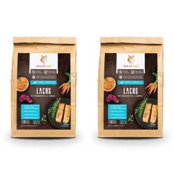 Zwei Säcke Wildfang-Hundefutter, beschriftet mit 'Lachs mit Süßkartoffel & Gemüse', mit Lachs, Süßkartoffeln und Gemüse. Jeder Sack wiegt 12 kg.