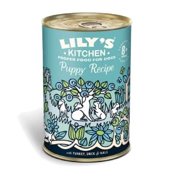 Can of Lily's Kitchen Puppy Recipe dog food, featuring a colorful illustration of dogs and plants, labeled with "with Turkey, Duck & Kale."
