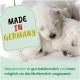 Zwei schlafende weiße Welpen neben einem Etikett mit der Aufschrift „Made in Germany“ und deutschem Text über Welpenmilch darunter.