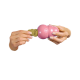 Hände, die ein goldenes, knochenförmiges Leckerli mit 'KONG'-Prägung in ein rosa KONG-Hundespielzeug stecken.