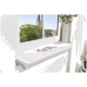 Eine gemütliche Fensterbank mit einem weichen weißen Haustierbett, auf dem eine schlafende Katze liegt, umgeben von Grün und einem Glockenturm im Hintergrund.