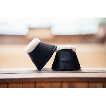 Zwei schwarze Pferdebeinschützer mit weißem Fleecefutter, mit einem "EQUINATE"-Logo, auf einer Holzoberfläche präsentiert.