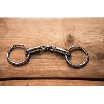 Ein glänzender Metallclip für Hundeleinen mit zwei Ringen, der auf einer Holzoberfläche liegt.