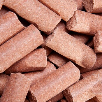 Nahaufnahme von braunen Haustierfutterpellets, die übereinander gestapelt sind und ihre zylindrische Form und strukturierte Oberfläche zeigen.