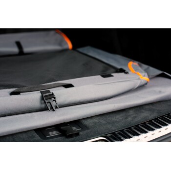 Eine Nahaufnahme eines grauen Autositzbezugs für Haustiere mit orangefarbenen Akzenten, der eine Netztasche und verstellbare Riemen aufweist, auf einem dunklen Autoinnenraum ausgelegt.