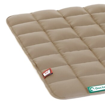 Ein beiges Haustierbett mit einem gesteppten Design, mit einem grünen "Doktor"-Logo und einem kleinen roten Etikett in der Ecke.