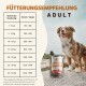 Hund neben Wildfang 'Lamm Pur' Dose und Fütterungstabelle mit dem Titel 'Fütterungsempfehlung ADULT' mit Gewichts-zu-Gramm-pro-Tag-Tabelle.