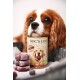 Ein Cavalier King Charles Spaniel legt seinen Kopf auf eine Dose "DOG'S LOVE" Hundefutter, neben ihm sind gefrorene Leckereien gestapelt.
