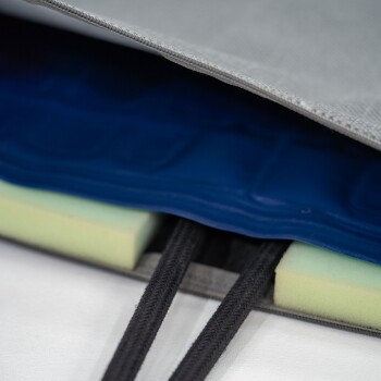 Nahaufnahme einer Kühlmatte für Haustiere mit einer grauen äußeren Schicht, blauen Gel-Einsatz und grünem Schaumstoffboden, mit sichtbaren schwarzen Riemen.