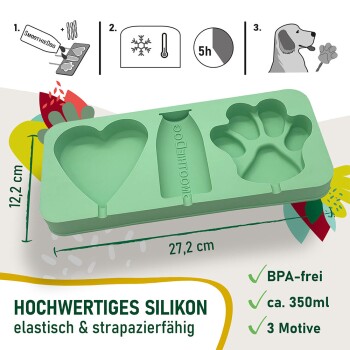 Eine Nahaufnahme eines Hundes, der einen herzförmigen Leckerbissen leckt, der von einer Hand gehalten wird, vor einem verschwommenen grünen Hintergrund.