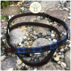 Eine braune Leder- und blau gewebte Hundeleine mit Kreuzmustern liegt auf glatten Steinen, mit dem Kipita-Logo darüber.