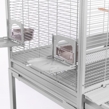 Eine Nahaufnahme eines silbernen Metall-Haustierkäfigs mit zwei abnehmbaren Futterschalen und einem geräumigen Innenraum mit horizontalen Stäben.