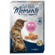 A tabby cat sits beside a package of "Soft Rolls Moments" cat treats, featuring salmon and chicken flavor, with four 10g portions.