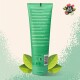 Grüne Tube mit Pet Head Knot Detangle Wassermelonen-Conditioner mit Inhaltsstoffdetails in mehreren Sprachen, umgeben von grünen Blättern.