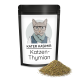 Schwarzer wiederverschließbarer Beutel mit illustriertem Katzenetikett, Text 'KATER KASIMIR' und 'Katzen-Thymian', davor ein Haufen getrockneter Kräuter