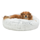 Ein Golden Retriever ruht sich bequem in einem flauschigen, runden, hellgrauen Hundebett aus.