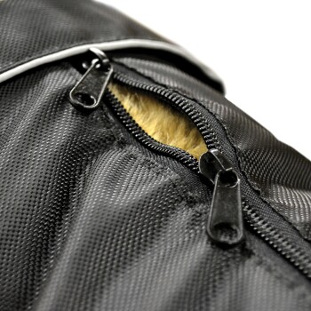 Nahaufnahme eines schwarzen Haustierträgers mit einem teilweise geöffneten Reißverschluss, der weiches, helles Fell im Inneren zeigt.