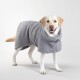 Ein Hund, der einen gemütlichen, grauen, waffle-musterigen Bademantel trägt, steht auf einem hellen Hintergrund.