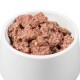 Eine weiße Haustierfutterschüssel, gefüllt mit feuchtem, stückigem Katzenfutter, das eine rosa-braune Farbe und eine strukturierte Optik aufweist.