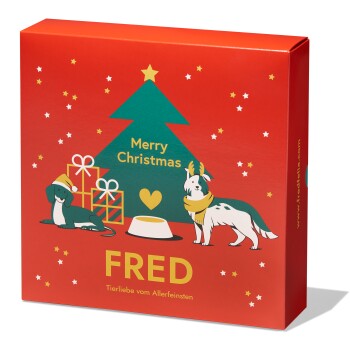 Eine rote Geschenkbox mit einem Weihnachtsbaum, "Frohe Weihnachten," zwei Hunden (einer mit Geweihen), beschriftet mit "FRED" und "Tierliebe vom Allerfeinsten."