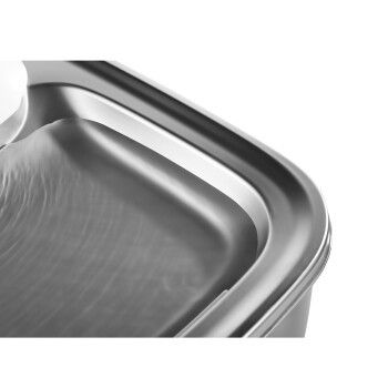Nahaufnahme einer eleganten, aus Edelstahl gefertigten Futterschüssel für Haustiere mit einer glatten, geschwungenen Kante und einem flachen Inneren, das Licht reflektiert.