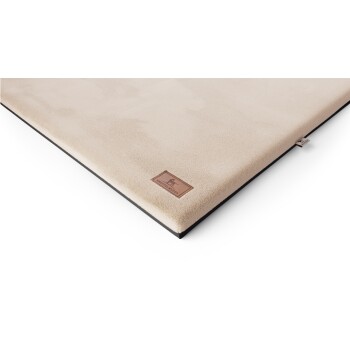 Ein beiges Haustierbett mit einer weichen, plüschigen Oberfläche und einem schwarzen Boden, mit einem braunen Etikett, das "KNUFFELHUPF" liest.