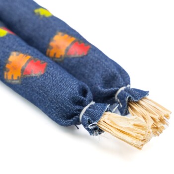 Zwei bunte Katzenminze gefüllte Spielzeuge, die in Denim-Stoff gewickelt sind, mit ausgefransten Enden, die Stroh ähneln, entworfen für Katzen zum Spielen.