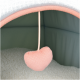 Un intérieur de lit pour animaux de compagnie confortable avec une base blanche douce et moelleuse et un jouet en forme de cœur rose suspendu.