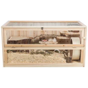 Ein zweistufiger Holzhaustierkäfig mit transparentem Frontbereich, ausgestattet mit einem Baumstamm, einer Plattform, einem Futternapf, Bettzeug, einem Rad und natürlicher Dekoration.