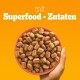 Eine Hand hält eine rosa Schüssel, gefüllt mit kleinen, braunen Haustierfutterkroketten, mit dem Text 'mit Superfood - Zutaten' auf einem orangefarbenen Hintergrund.
