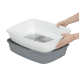 Une personne tient une litière pour chat à deux niveaux, avec un plateau supérieur blanc à fond fendu et un plateau de base gris collectant la litière.