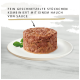 Hundefutter auf einem weißen Teller, bestehend aus fein zerkleinertem Fleisch mit einem Hauch von Sauce, mit deutschem Text zur Produktbeschreibung.