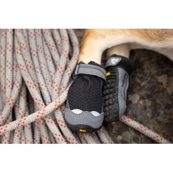Schwarze und graue Hundeschuhe mit Vibram-Sohlen, die auf einem strukturierten grauen und roten Seil-Hintergrund ruhen.