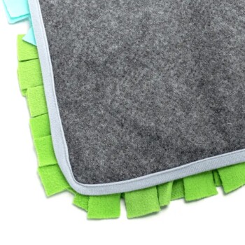 Graue Haustierdecke mit bunten grünen und blauen Fleecefransen entlang der Ränder.