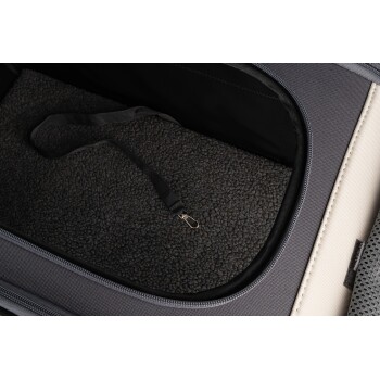 Nahaufnahme des Innenraums einer Haustiertrage mit einer weichen, dunklen Fleeceauskleidung und einem schwarzen Gurt zur Sicherung von Haustieren.