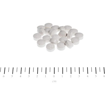 Kleine weiße runde Tabletten auf weißem Hintergrund über einem Zentimeterlineal, markiert 0–6 cm, beschriftet cm