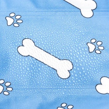 Blauer Stoff mit weißen Knochen- und Pfotenabdruckmustern, mit Wassertropfen auf der Oberfläche.