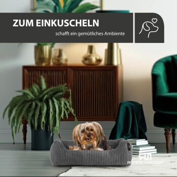 Ein kleiner Hund ruht sich in einem gemütlichen grauen Haustierbett aus, umgeben von stilvoller Wohnkultur, mit dem Text 'ZUM EINKUSCHELN schafft ein gemütliches Ambiente' darüber.